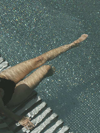 Bild von Beinen in einem klaren Pool.