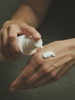 Nahaufnahme von Bodylotion, die auf Handaußenfläche gegeben wird.