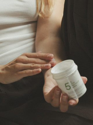 Eine Frau cremt ihren Arm mit 5 % Urea-Harnstoffsalbe ein
