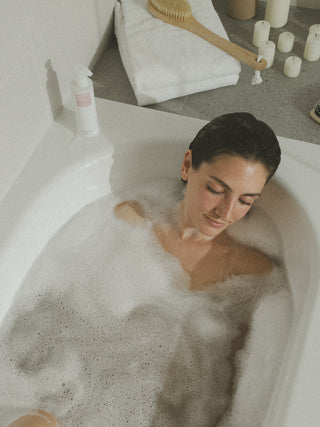 Frau liegt entspannt in der Badewanne. Ihre Augen sind geschlossen.