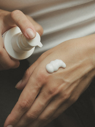 Nahaufnahme von Bodylotion, die auf Hand gegeben wird.