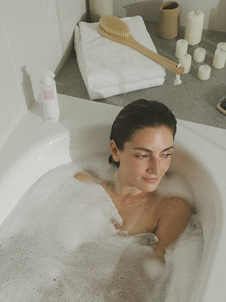 Frau liegt in der Badewanne. Ihr Gesicht ist entspannt.