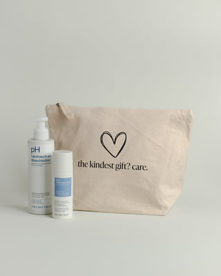Hellbrauner Baumwoll-Kosmetikbeutel mit einem schwarz umrandeten Herz und Aufschrift "the kindest gift? care." Davor stehen 2 Hautpflegeprodukte von Phametra Cosmetics