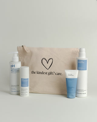 Hellbrauner Baumwoll-Kosmetikbeutel mit einem schwarz umrandeten Herz und Aufschrift "the kindest gift? care." Davor stehen 4 Hautpflegeprodukte von Phametra Cosmetics.