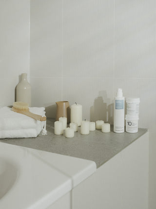 Badewannenrand, worauf Kerzen, Bodylotion und zwei Ureasalben stehen.