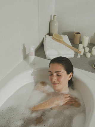Junge Frau liegt entspannt in einer Badewanne.