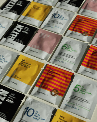 Verschiedene Phametra Produktproben, darunter Sonnencreme LSF 50+, Schutz- und Pflegecreme, Urea Harnstoff-Salbe und speziell formulierte Produkte für Gesicht und empfindliche Haut, in bunten Einzelsachets angeordnet