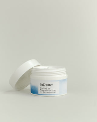 Geöffneter weißer Plastiktiegel mit weiß/blauem Etikett mit Phametra Cosmetics Fußbutter