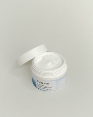 Geöffneter, weißer Plastiktiegel von oben fotografiert mit weiß/blauem Etikett mit Phametra Cosmetics Fußbutter