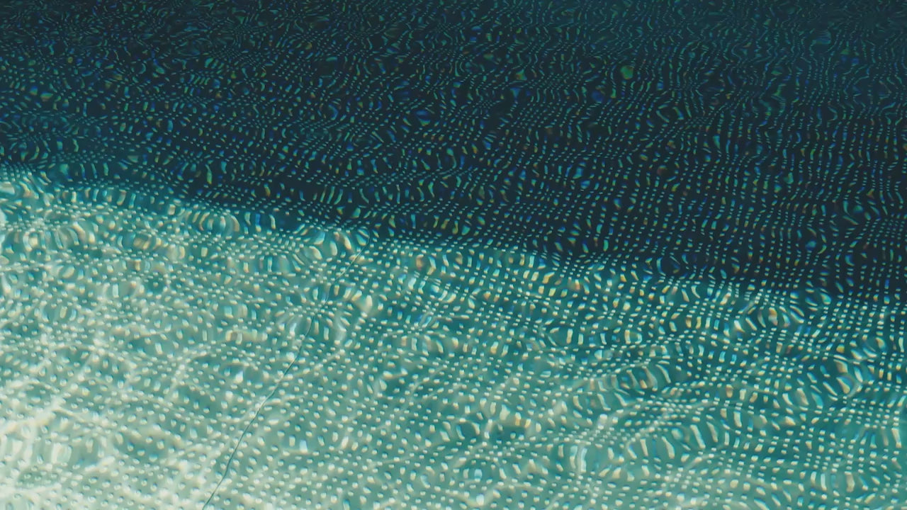 Eine Frau im dunklen Badeanzug schwimmt in einem Pool
